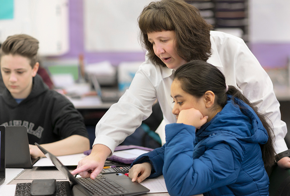 Open Up Resources 6-8 Math Teacher showing student how to solve a math problem on laptop