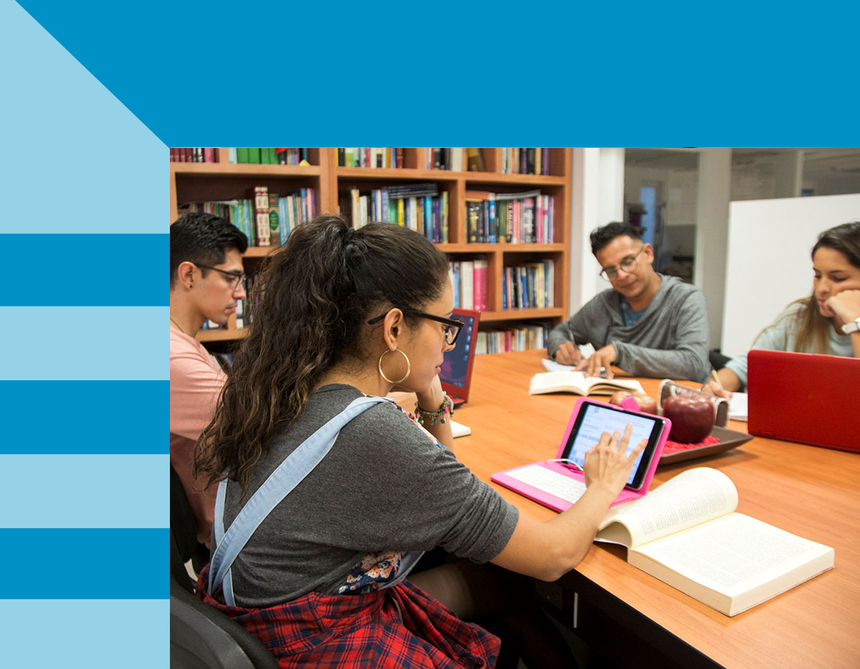 A graphic with a photo of students engaged in study and discussion at a library. One student has a tablet and book opened together.